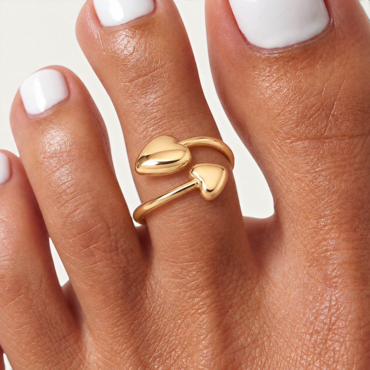 Feetz & Co. Adore adjustable gold toe ring featuring two polished heart charms on a stainless steel band.