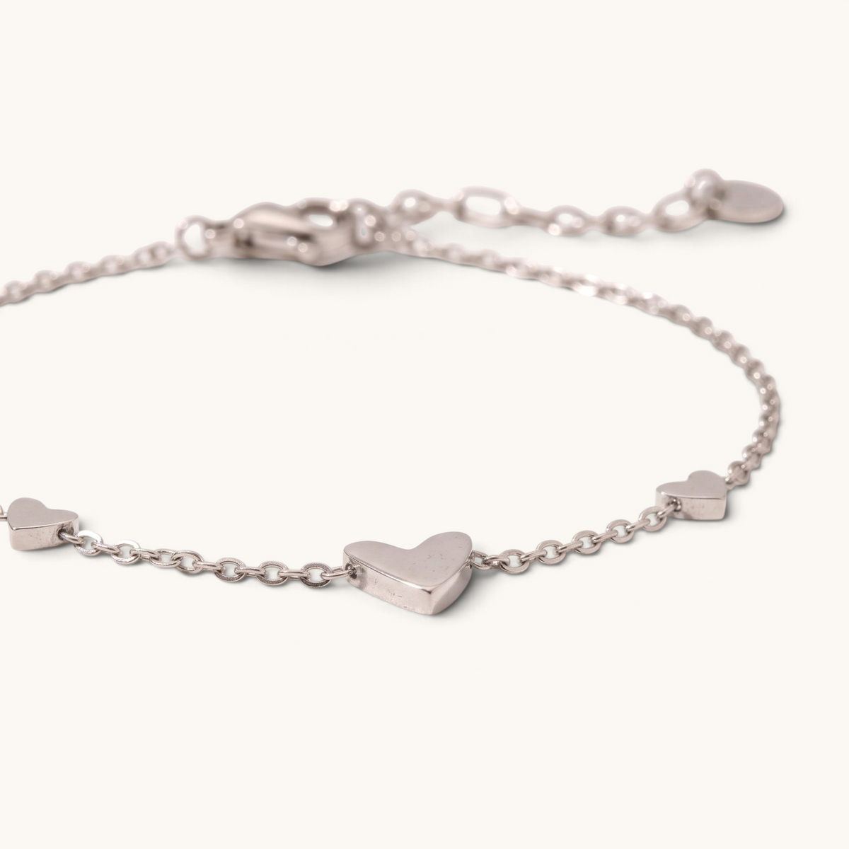 Feetz & Co. Amore silver-tone stainless steel anklet featuring three delicate heart charms on a fine cable chain.