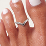 Feetz & Co. silver-plated stainless steel arrow toe ring with a V-peak design worn on a toe with white nail polish.