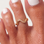 Feetz & Co. Marée gold adjustable toe ring with a wave design and tiny sparkling stones worn on a toe.
