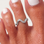 Feetz & Co. Marée adjustable silver toe ring with a wave design and tiny sparkling stones on a person's toe.