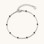 Feetz & Co. Onice anklet featuring a silver-tone stainless steel chain with small black beads and a logo charm.