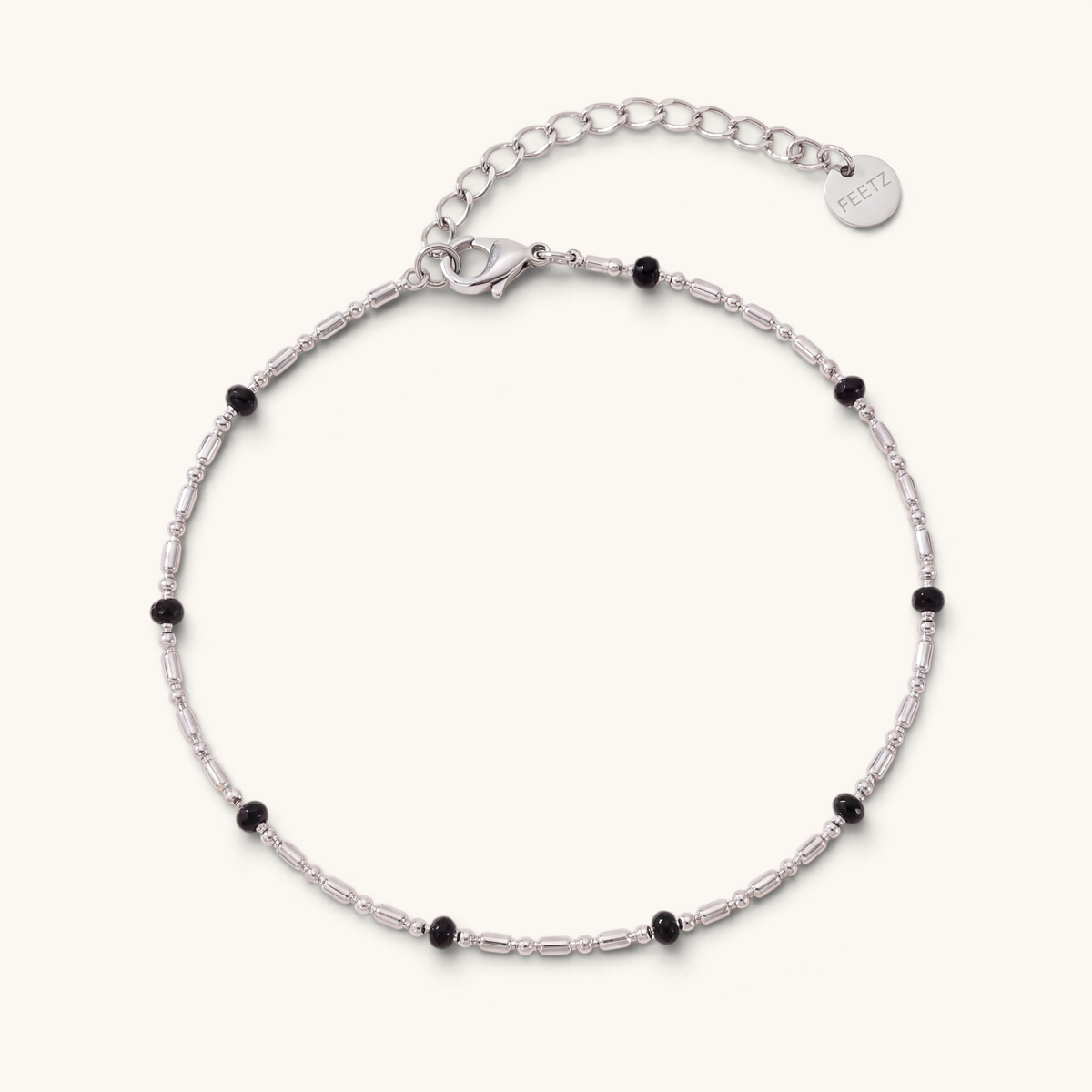 Feetz & Co. Onice anklet featuring a silver-tone stainless steel chain with small black beads and a logo charm.