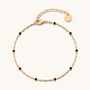 Feetz & Co. Onice anklet featuring a gold-tone stainless steel chain with small black beads and a branded charm.