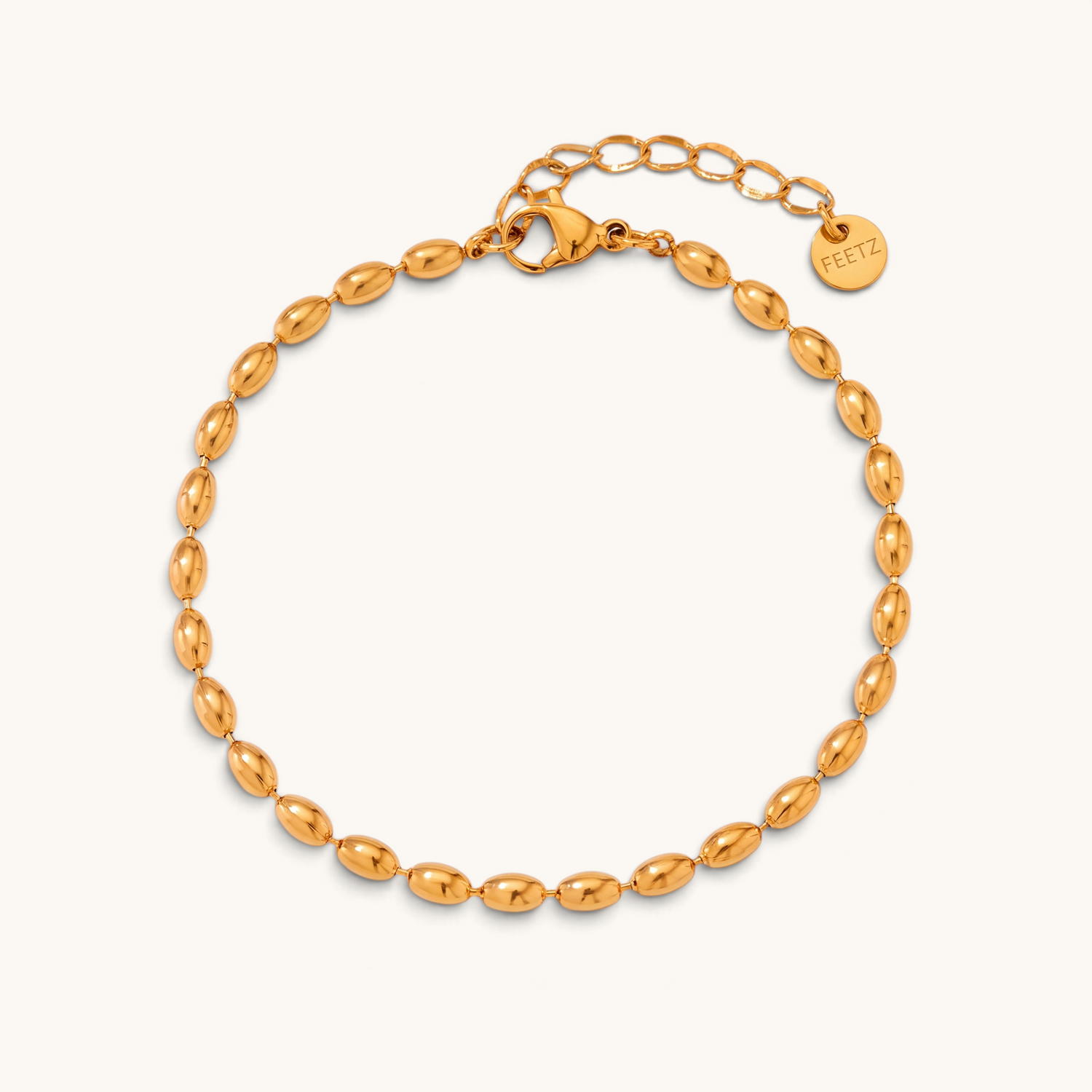 Feetz & Co. Riso anklet featuring a row of polished gold-tone oval beads made from water-resistant stainless steel.