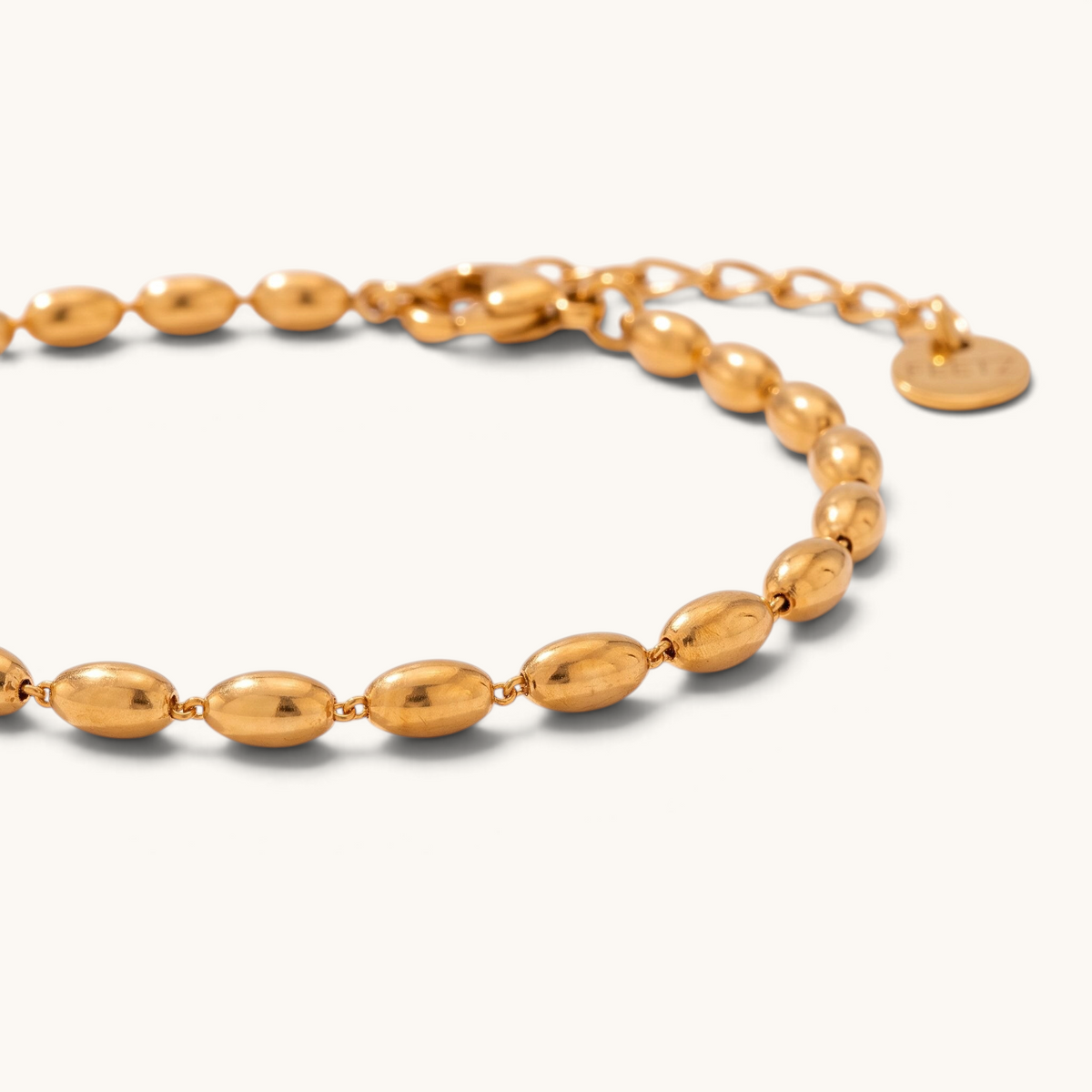 Feetz & Co. Riso anklet featuring polished oval gold-tone stainless steel beads on a delicate chain.